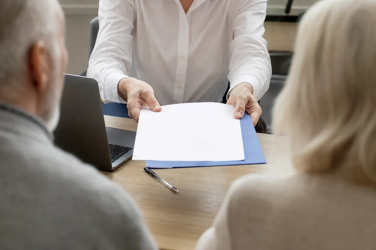 Conseiller présentant un contrat de prévoyance à un couple de seniors